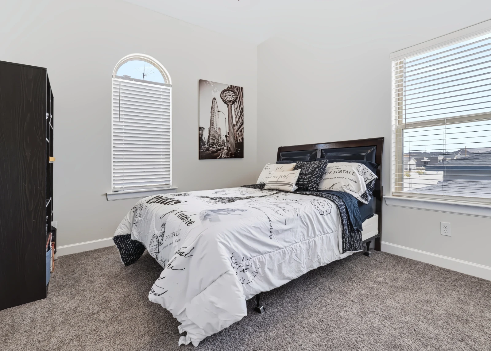 Guest bedroom with patterned bedding and two sunlit windows
